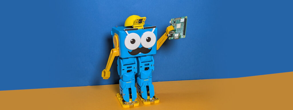 Marty the Robot with a camera hat, holding a Raspberry Pi
